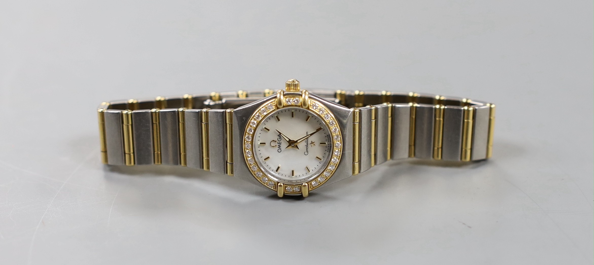 A lady's modern steel and yellow metal Omega Constellation quartz wrist watch and bracelet, with mother of pearl dial and diamond set bezel, with box and some papers, including precious gem certificate